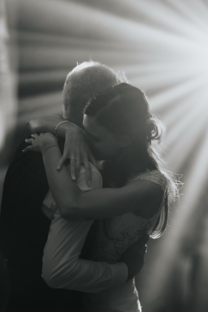 An embrace on the dance floor among beams of light, black and white