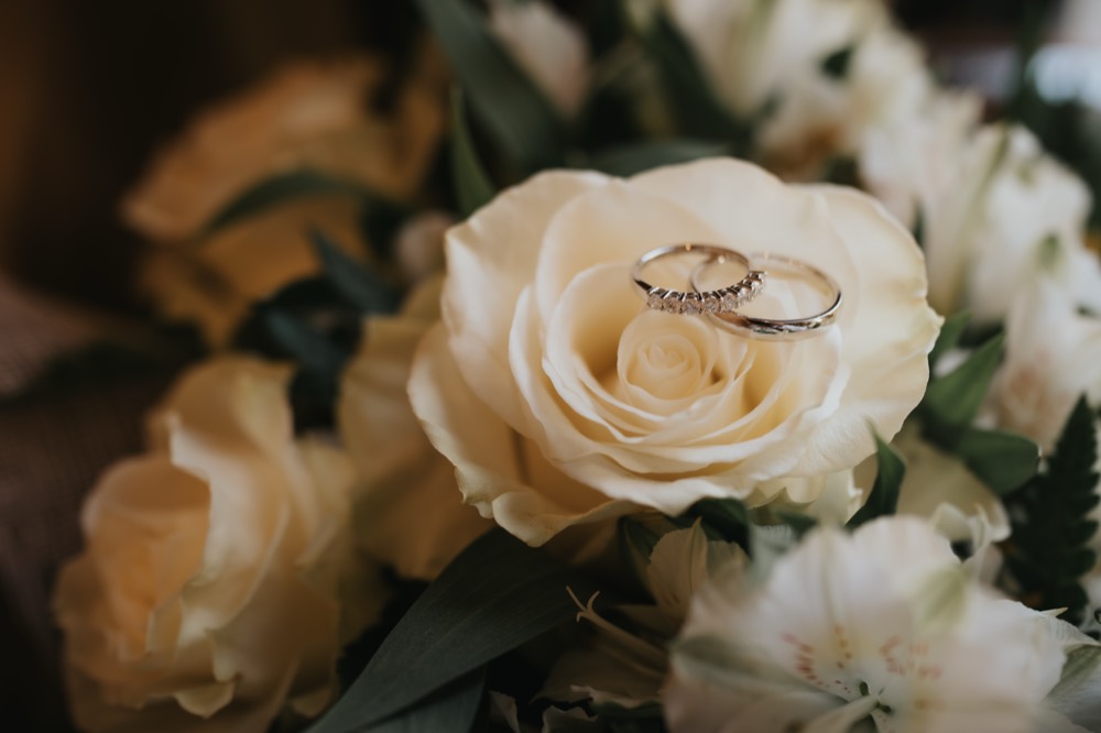Wedding rings resting on a white rose