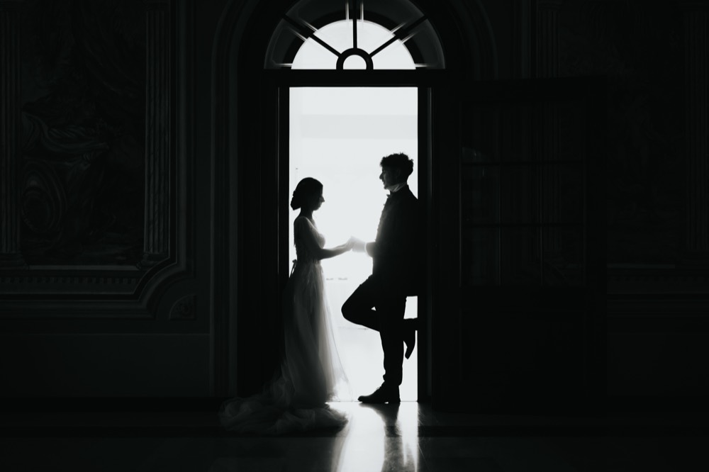 Gli sposi in silhouette nel vano luminoso di una porta ad arco
