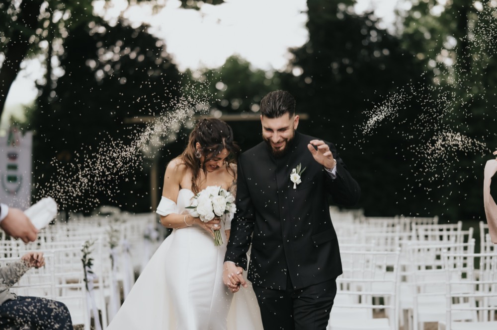 The couple among white chairs under falling rice