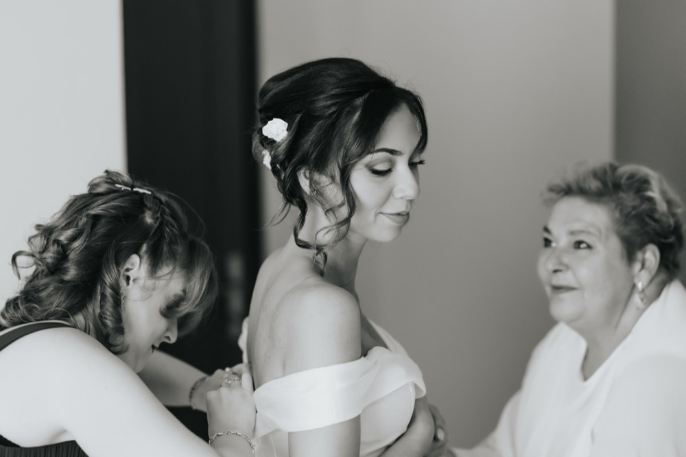 The bride being helped into her dress, black and white