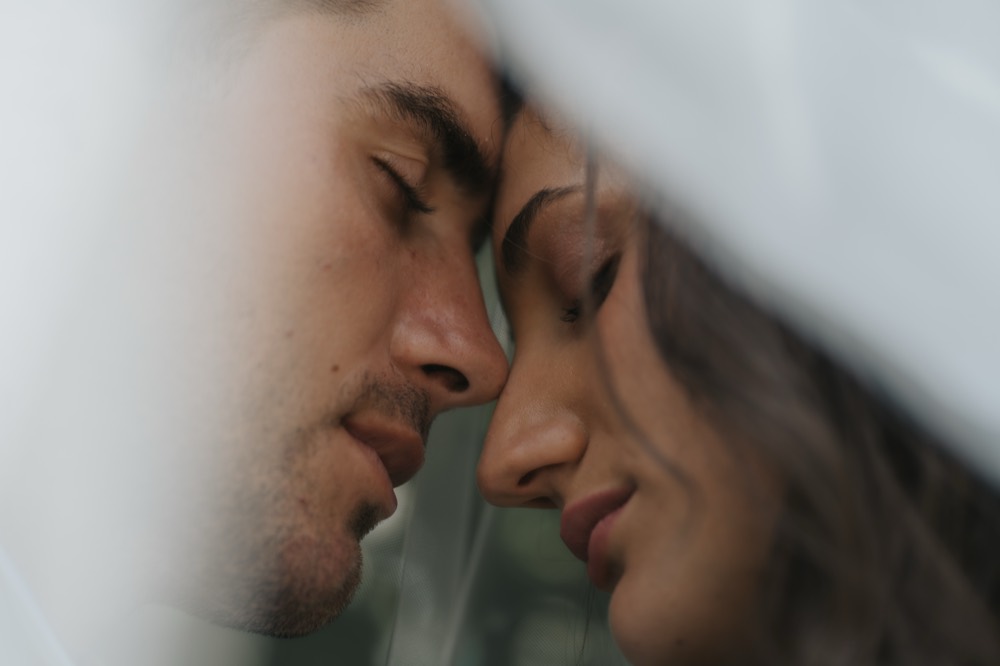The couple’s faces close together under the veil